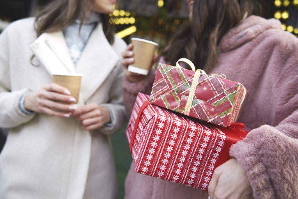 Two Friends On Christmas Market Carrying Christmas Presents